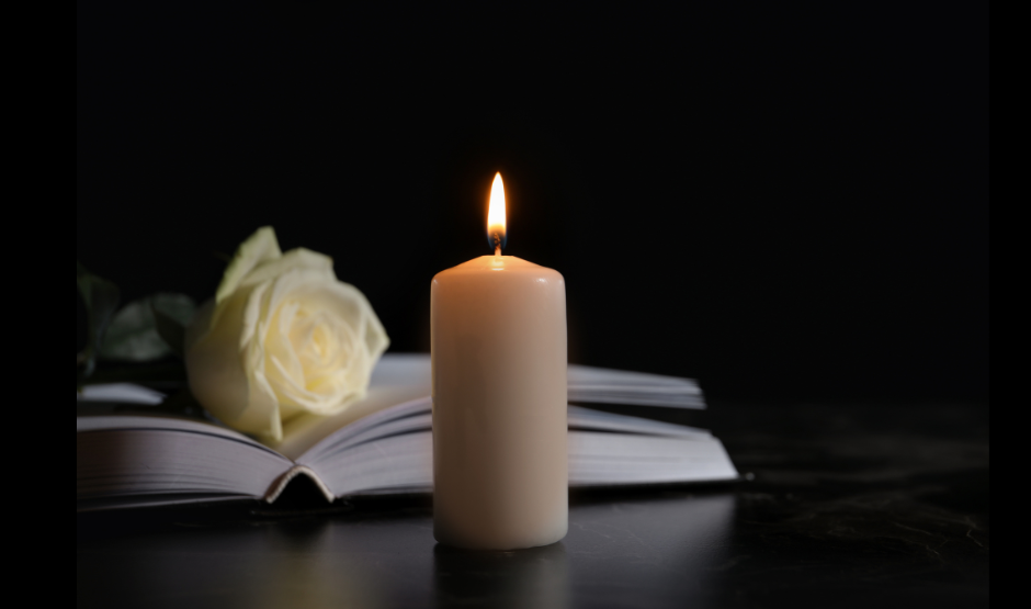 white rose on an open bible and lit candle