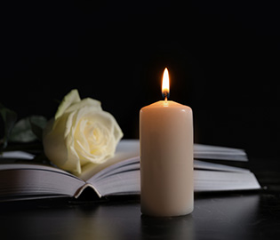 Lit candle with open bible and white rose
